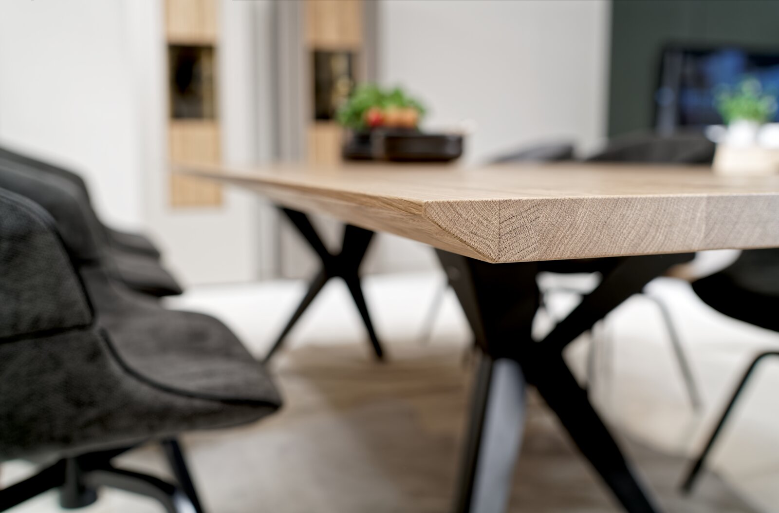 Nahaufnahme eines modernen Esstisches mit Holzplatte und schwarzen Metallbeinen, seitliche Perspektive.
