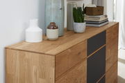 Nahaufnahme eines modernen, zweifarbigen Sideboards aus Holz mit dekorativen Vasen und Pflanzen darauf, seitliche Perspektive.
