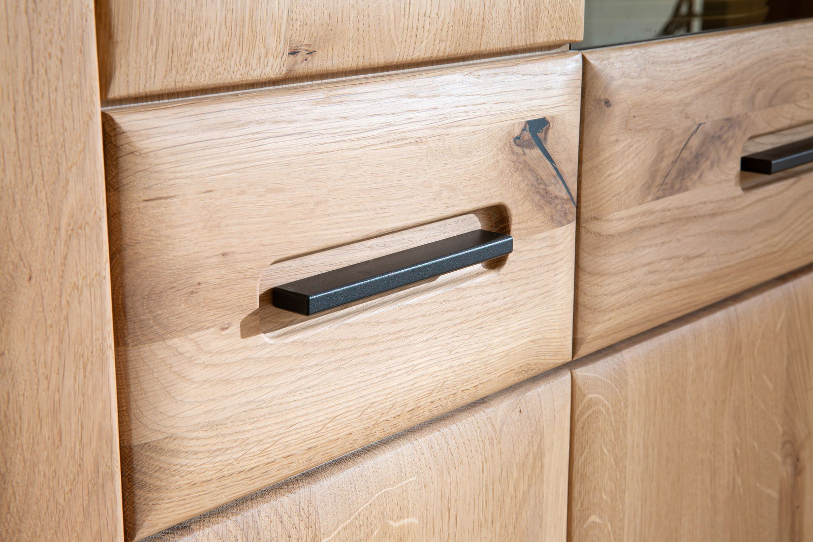 Nahaufnahme eines Holz-Sideboards mit modernen, schwarzen Griffen, aus einer schrägen Perspektive fotografiert.