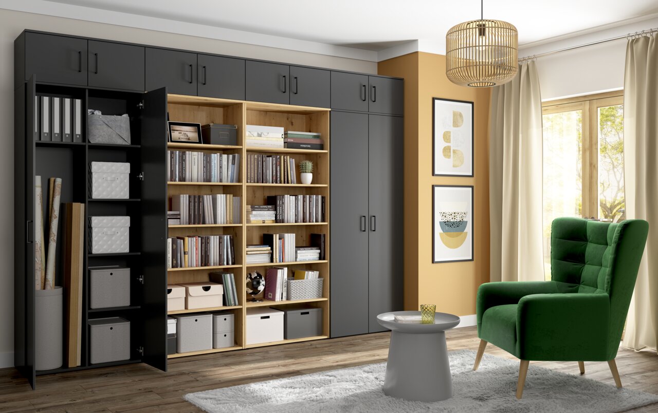 Carryhome Mehrzweck-/Vorratsschrank MULTISTAURAUM Moderne Wohnzimmereinrichtung mit einem großen, grauen Mehrzweckschrank und einem offenen Bücherregal in Holzoptik, daneben ein grüner Sessel und ein kleiner runder Tisch. Perspektive von vorne.