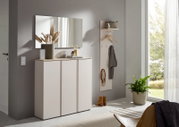 Modernes Flur-Set mit weißer Schuhkommode und Wandgarderobe mit Ablage, Haken und Kleiderbügeln, darüber ein rechteckiger Spiegel; Perspektive: frontale leicht seitliche Ansicht im hellen Eingangsbereich