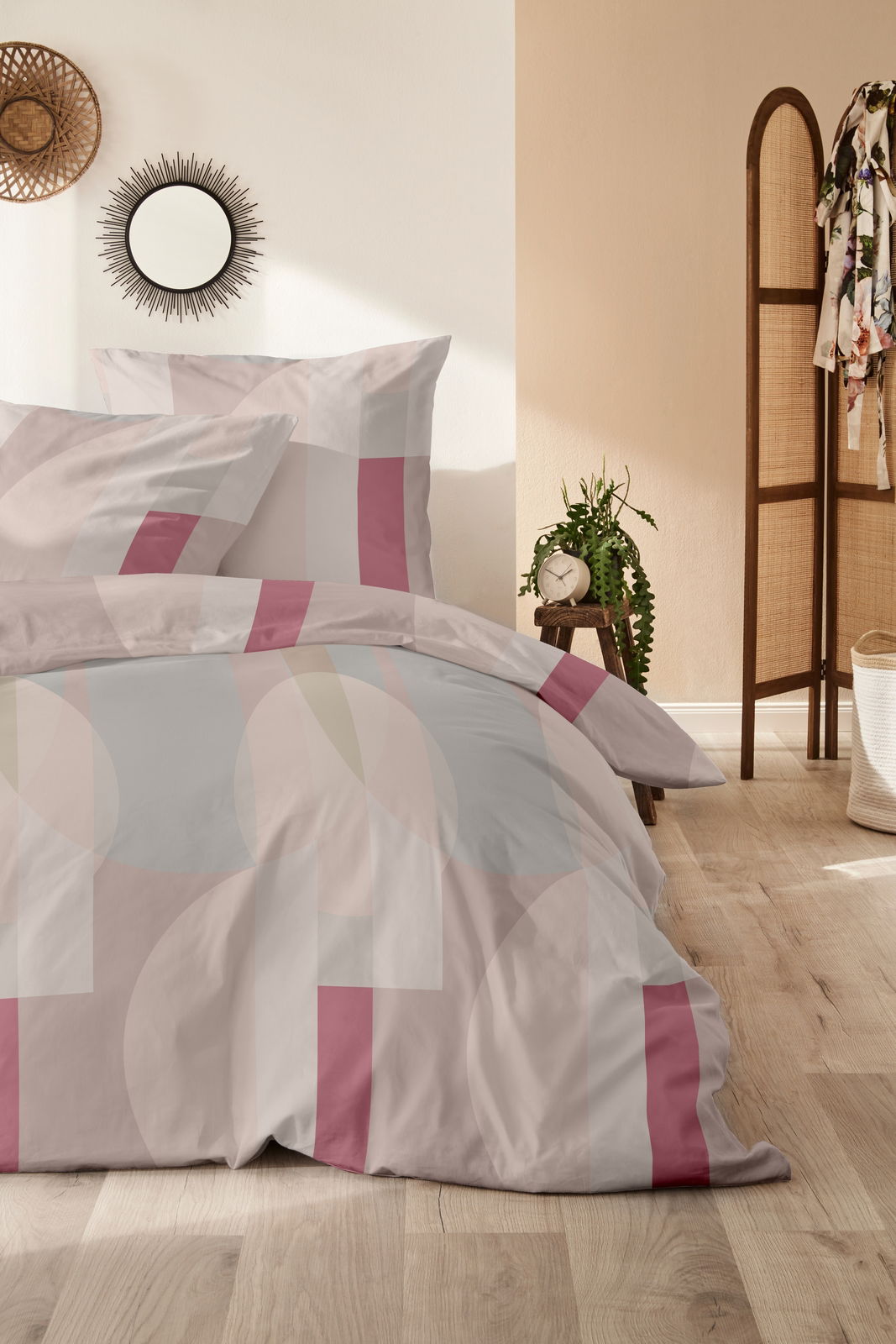 Primera Bettwäsche 135x200cm Bettwäsche-Set mit geometrischem Muster in Rosa- und Beigetönen, fotografiert in einem stilvoll eingerichteten Schlafzimmer mit Holzboden und Dekoration.