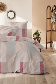 Bettwäsche-Set mit geometrischem Muster in Rosa- und Beigetönen, fotografiert in einem stilvoll eingerichteten Schlafzimmer mit Holzboden und Dekoration.