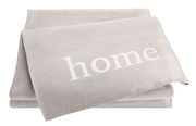 Graue Wohndecke mit dem Wort 'home' in weißer Schrift, aus einer leicht seitlichen Perspektive fotografiert.