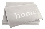 Graue Wohndecke mit dem Wort 'home' in weißer Schrift, aus einer leicht seitlichen Perspektive fotografiert.