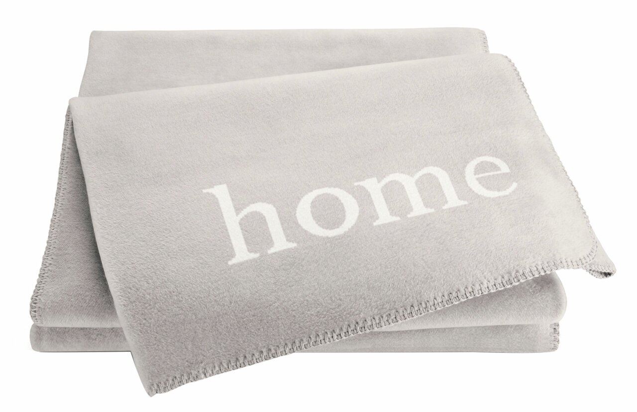 Graue Wohndecke mit dem Wort 'home' in weißer Schrift, aus einer leicht seitlichen Perspektive fotografiert.