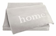 Graue Wohndecke mit dem Wort 'home' in weißer Schrift, aus einer leicht seitlichen Perspektive fotografiert.