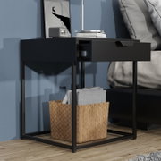 Schwarzer Nachttisch/Beistelltisch im modernen Design mit Metallgestell und geöffneter Schublade neben einem Bett, frontale leicht seitliche Perspektive