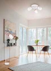 Deckenstrahler mit drei weißen, gemusterten Lampenschirmen in einem modernen Wohnzimmer, seitliche Perspektive.
