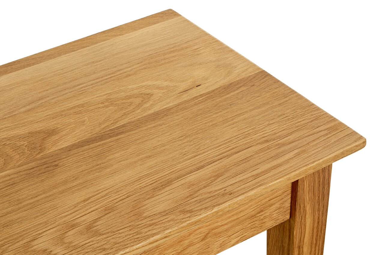 Detailaufnahme einer Holz-Tischplatte mit sichtbarer Maserung, schräg von oben aus der Ecke fotografiert (Nahaufnahme).