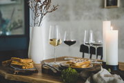 Elegantes Chardonnayglas auf einem gedeckten Tisch mit Waffeln und Kerzen, seitliche Perspektive.