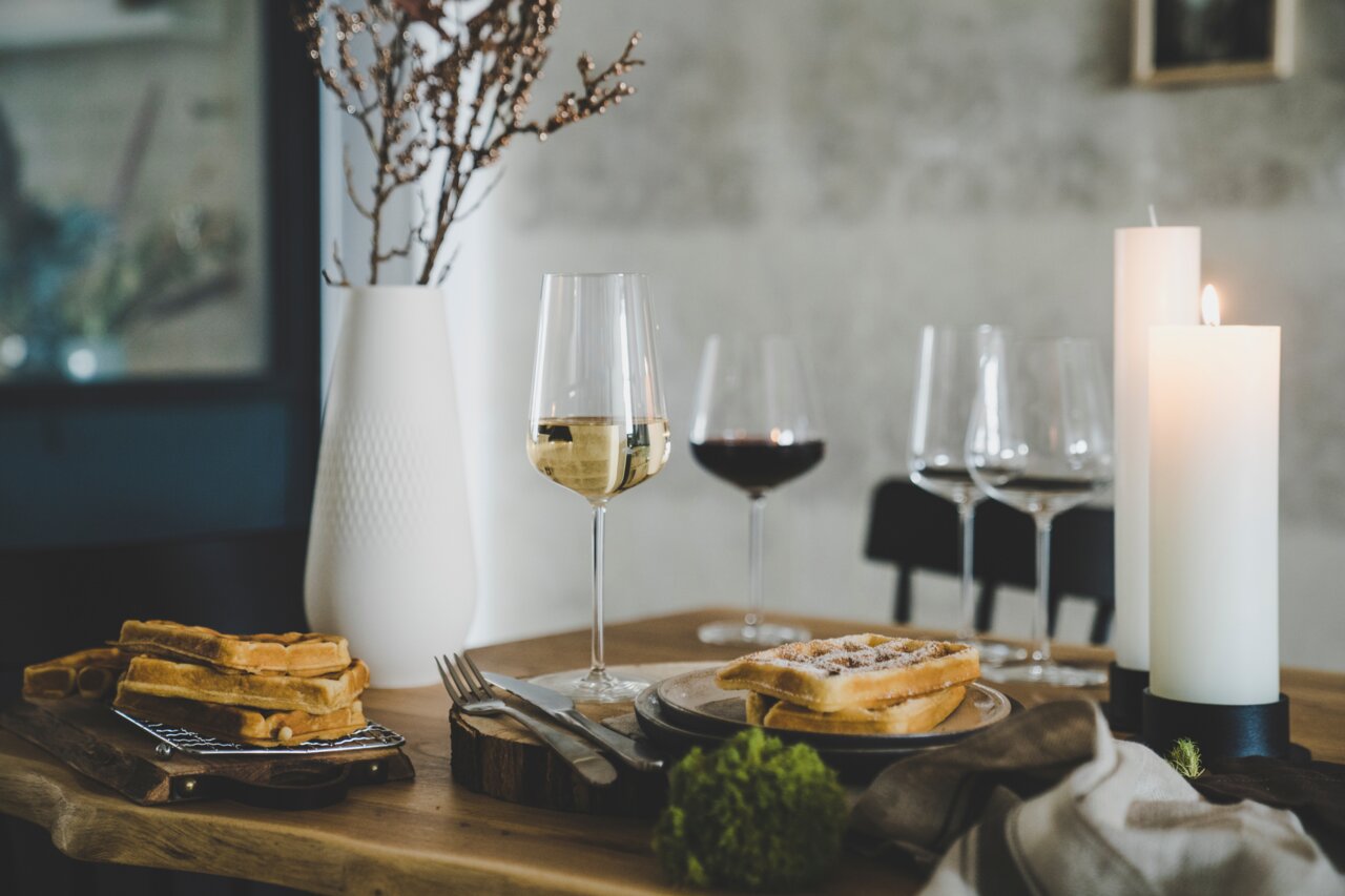 SCHOTT ZWIESEL Chardonnayglas VERVINO Elegantes Chardonnayglas auf einem gedeckten Tisch mit Waffeln und Kerzen, seitliche Perspektive.