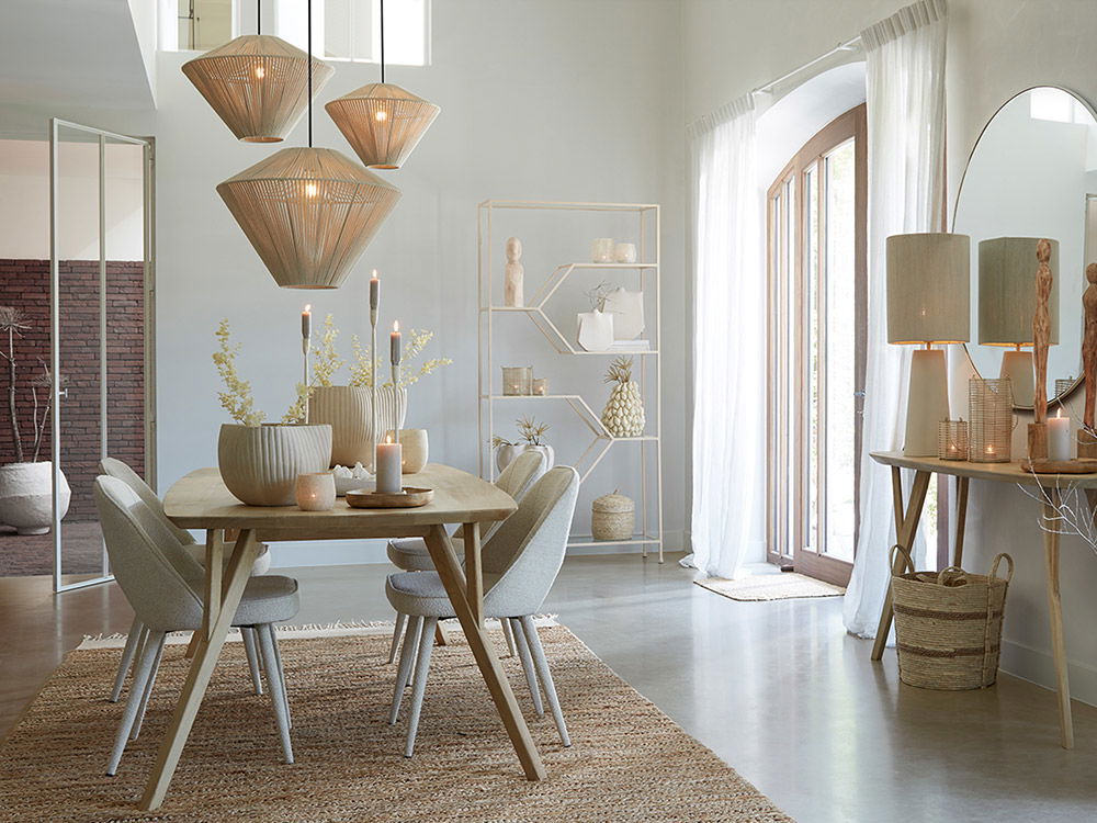 Heller Essbereich mit Holztisch, gepolsterten Stühlen, Rattanlampen und natürlicher Deko in warmen Beigetönen.