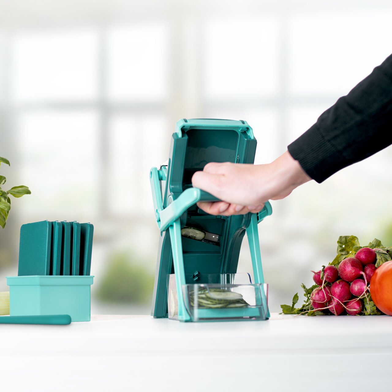 Nicer Dicer Mando, set van 10 stuks, in gebruik, zijaanzicht, met gesneden groenten en accessoires.