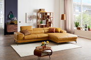 Moderne Longchairkombination in senfgelbem Leder, perspektivisch von vorne rechts fotografiert, in einem stilvoll eingerichteten Wohnzimmer mit Holzboden und großen Fenstern.