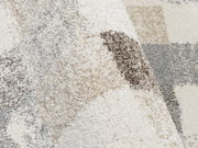 Nahaufnahme eines Frisé-Teppichs mit einem Muster in Beige-, Grau- und Cremetönen, aus einer schrägen Perspektive fotografiert.