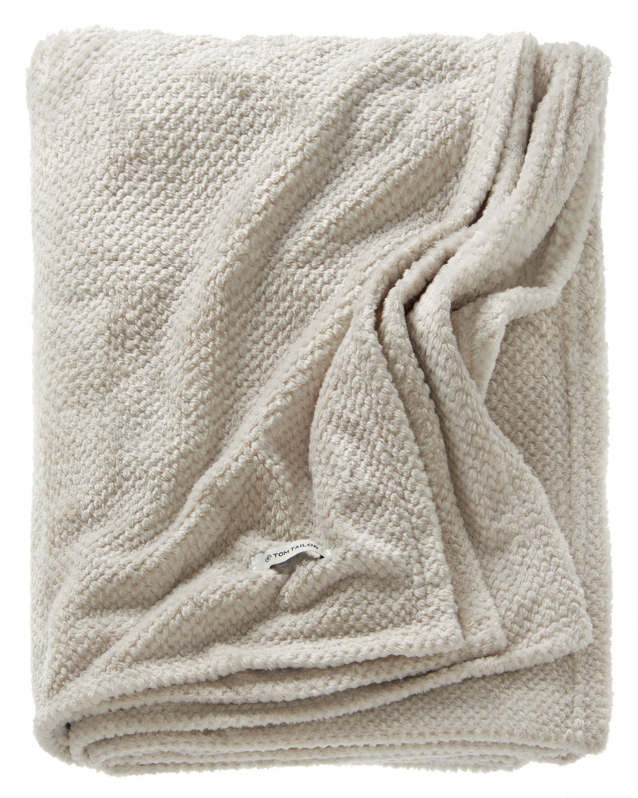 Weiche, cremefarbene Strickdecke in gefalteter Perspektive mit sichtbarem Etikett.