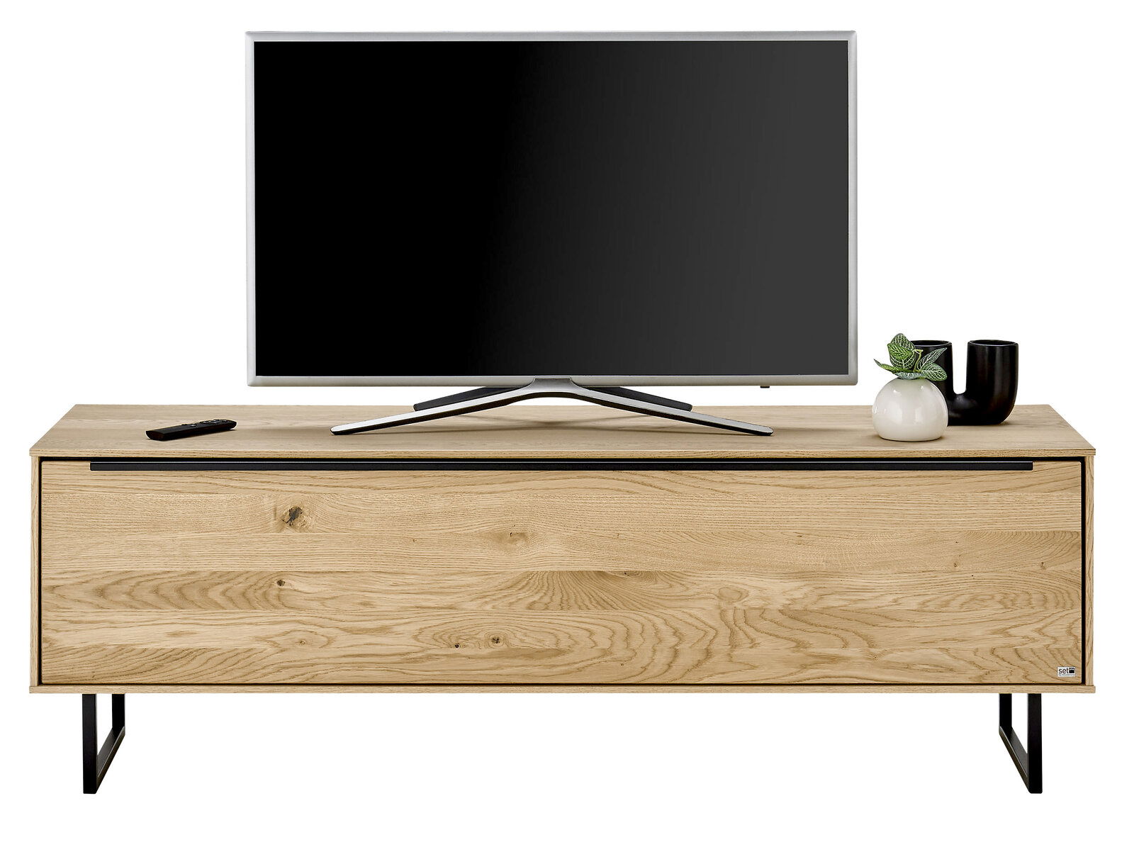 Frontale Ansicht eines kleinen TV-Lowboards aus Holz mit schwarzem Metallgestell, darauf ein Flachbildfernseher und Dekoration.