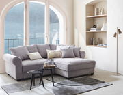 Gemütliche Rundecke MAUREEN in einem hellen Wohnzimmer mit großen Fenstern und Blick auf den See, seitliche Perspektive