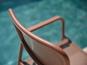 Rückansicht eines braunen Stapelsessels am Pool, Fokus auf die geschwungene Rückenlehne.