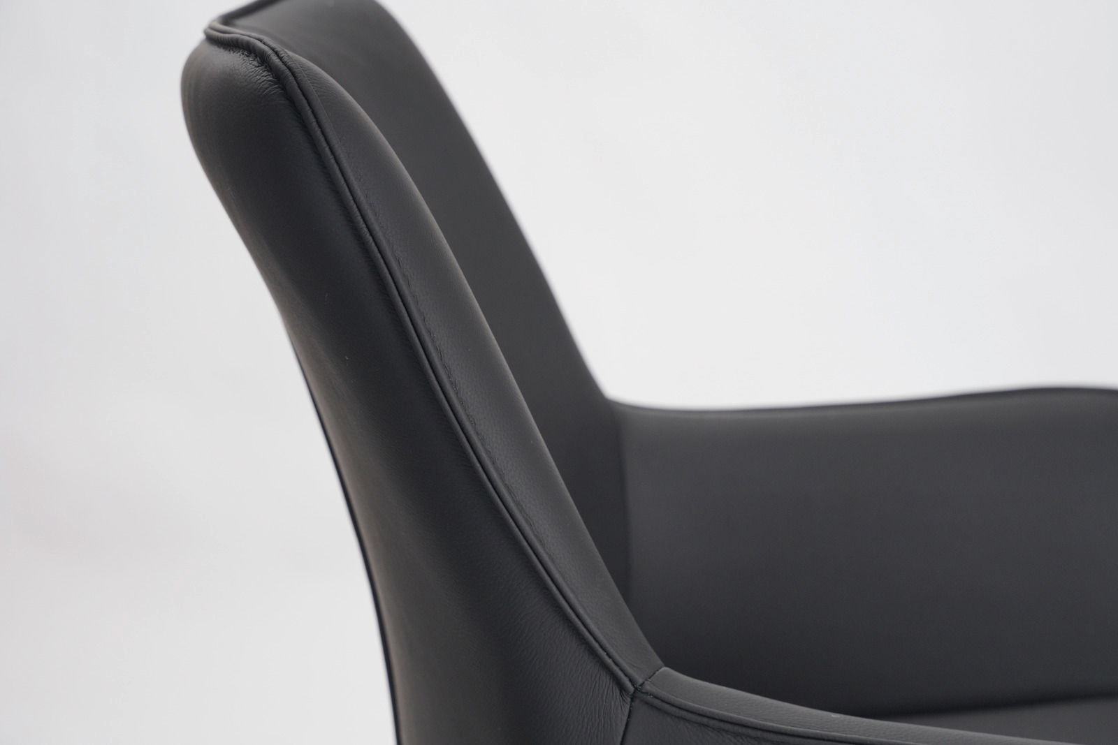 Nahaufnahme eines schwarzen Barhockers mit gepolsterter Rückenlehne, seitliche Perspektive