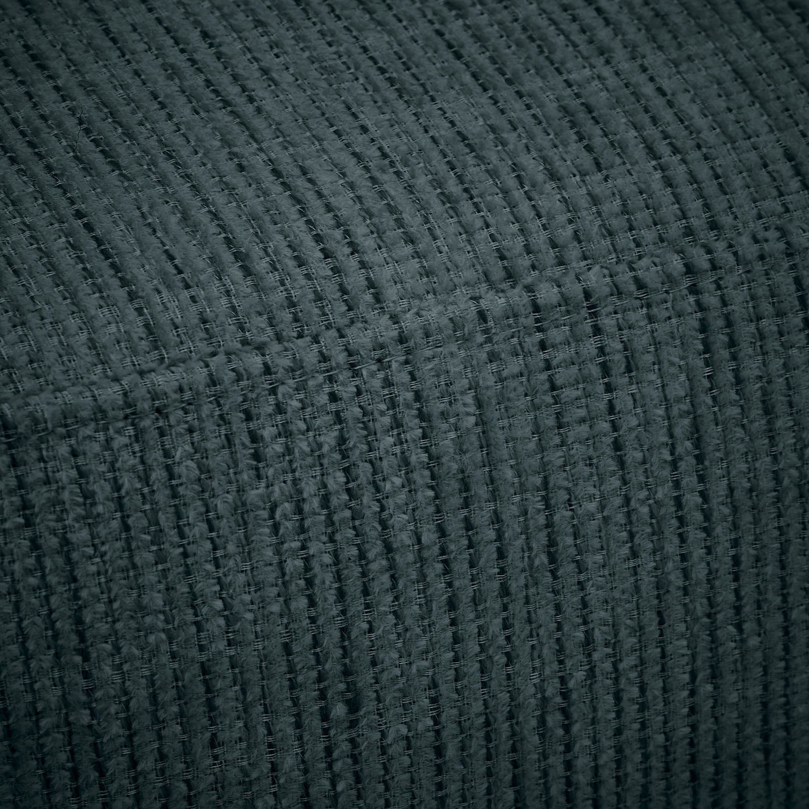 Nahaufnahme eines strukturierten, dunkelgrauen Stoffes, der für eine Recamiere verwendet wird.