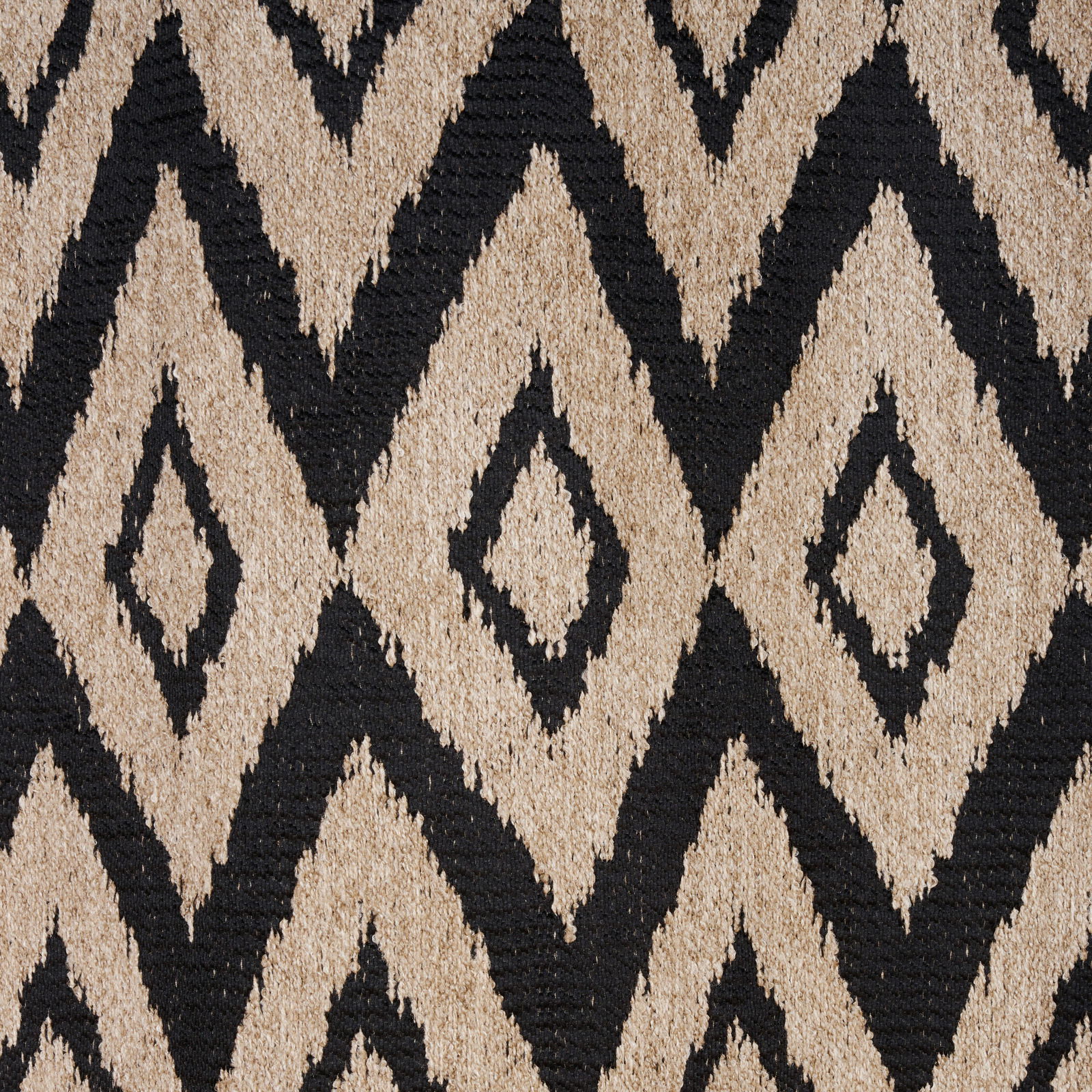 Nahaufnahme eines Ösenschals mit geometrischem Rautenmuster in Schwarz und Beige, von oben betrachtet.