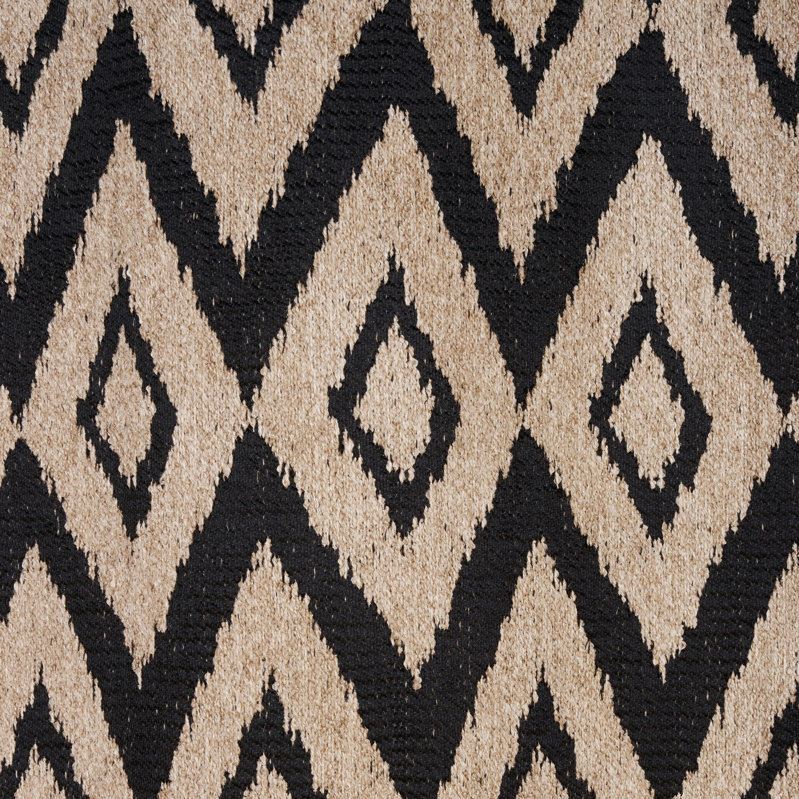 Nahaufnahme eines Ösenschals mit geometrischem Rautenmuster in Schwarz und Beige, von oben betrachtet.