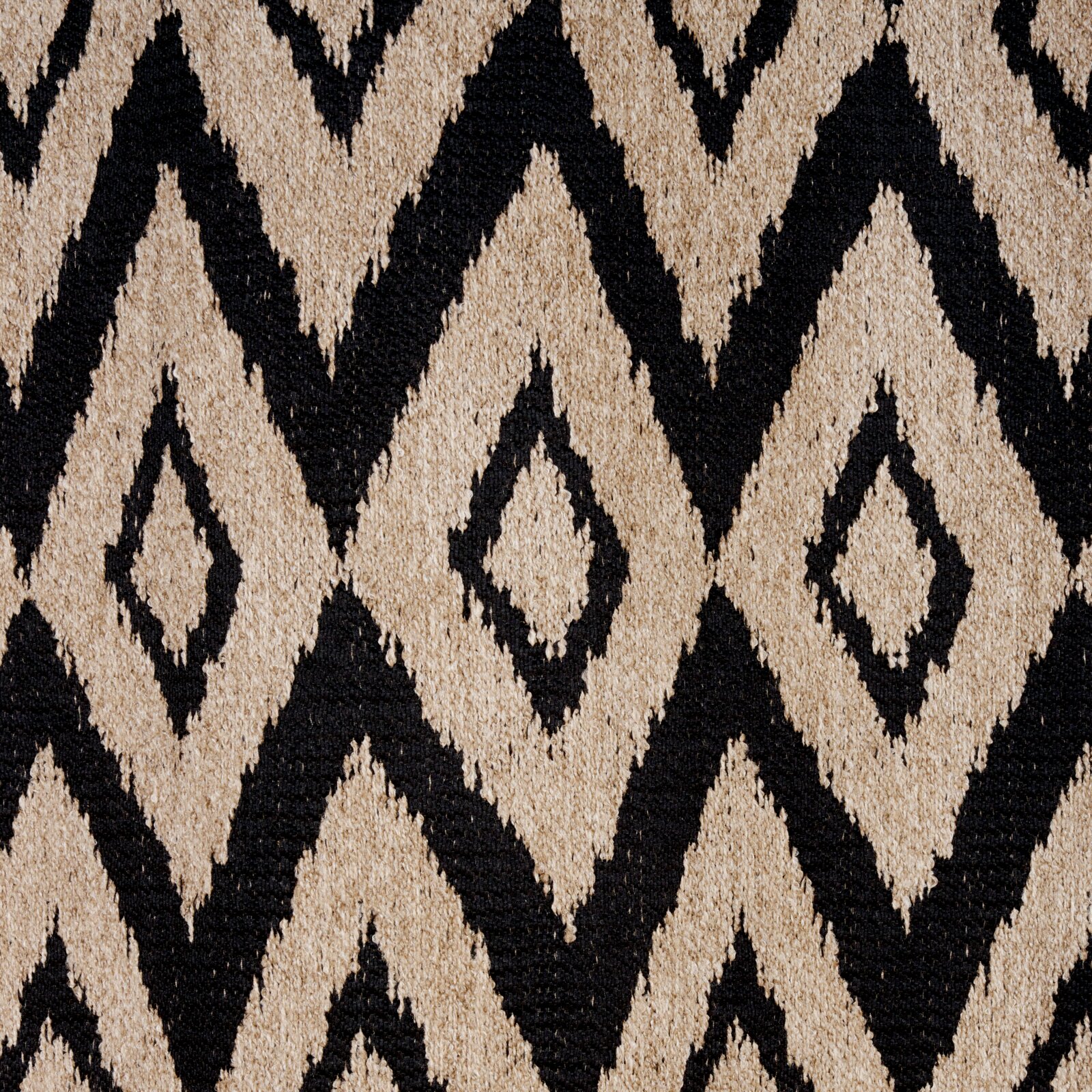Nahaufnahme eines Ösenschals mit geometrischem Rautenmuster in Schwarz und Beige, von oben betrachtet.