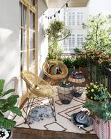 Gemütliche Balkonansicht mit zwei runden Beistelltischen aus Metall und Glas, umgeben von Rattan-Stühlen, Pflanzen und Dekorationen.