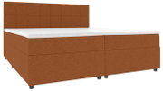 Bruin boxspringbed met een gestoffeerd hoofdeinde met vierkante stiksels en een witte matrashoes, schuin van linksvoor gefotografeerd