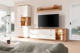 Modernes TV-Lowboard in hellem Holz und Weiß, frontal fotografiert, mit integriertem Stauraum und dekorativen Elementen.