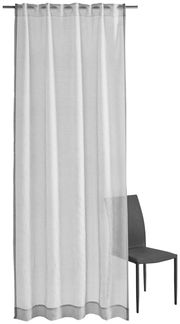 Grauer Vorhang mit Allover-Ornamentmuster, frontal fotografiert, neben einem Stuhl.