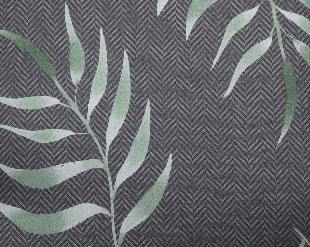 Nahaufnahme einer Hochlehnerauflage mit grauem Fischgrätmuster und grünem Blattdesign.