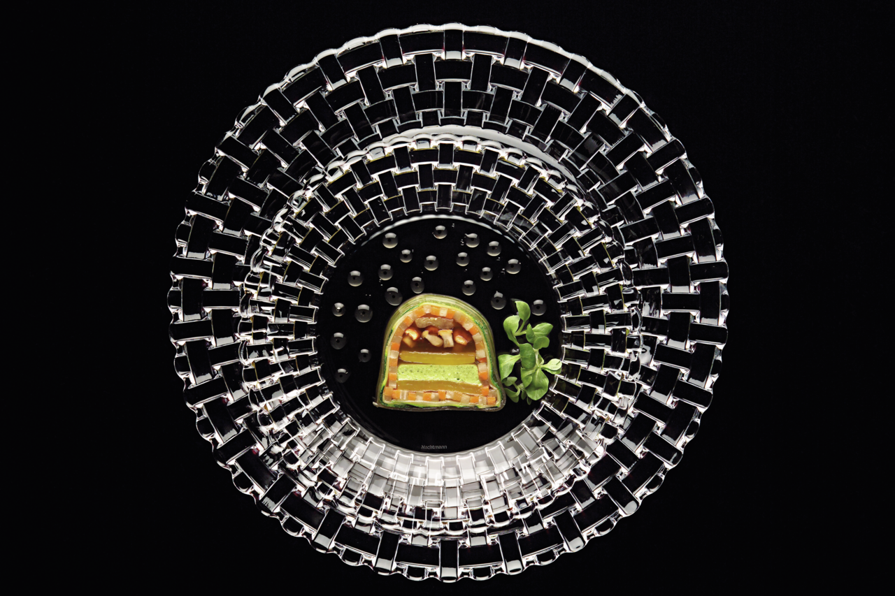 Vogelperspektive auf einen eleganten Platzteller aus der Bossa Nova Kollektion mit einem kunstvoll angerichteten Gericht in der Mitte.