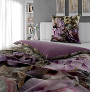 Wendebettwäsche mit floralem Muster in Lila- und Beigetönen, auf einem Bett in einem modernen Schlafzimmer mit Blick auf das Kopfkissen und die Bettdecke.
