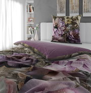 Wendebettwäsche mit floralem Muster in Lila- und Beigetönen, auf einem Bett in einem modernen Schlafzimmer mit Blick auf das Kopfkissen und die Bettdecke.