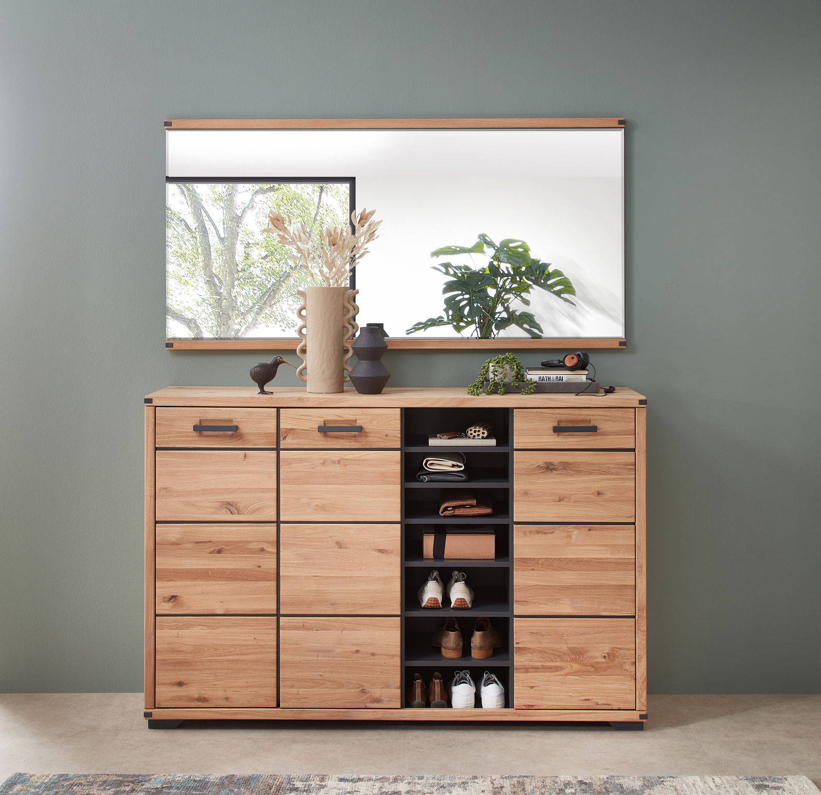 Frontale Ansicht eines XL-Schuhschranks aus Holz mit mehreren Fächern, dekoriert mit Vasen und Pflanzen, vor einem großen Spiegel.