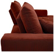 Nahaufnahme einer roten, gerippten Sofaecke mit zwei großen Kissen, seitliche Perspektive.