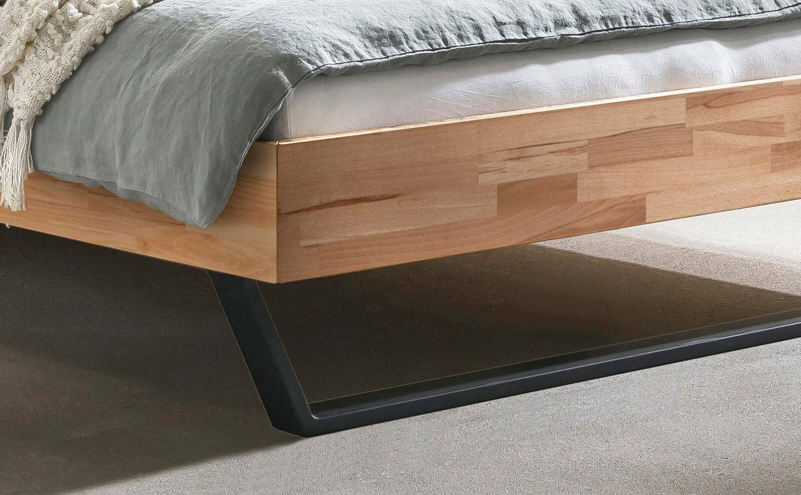 Nahaufnahme eines modernen Bettgestells aus Holz mit Metallbeinen, seitliche Perspektive.