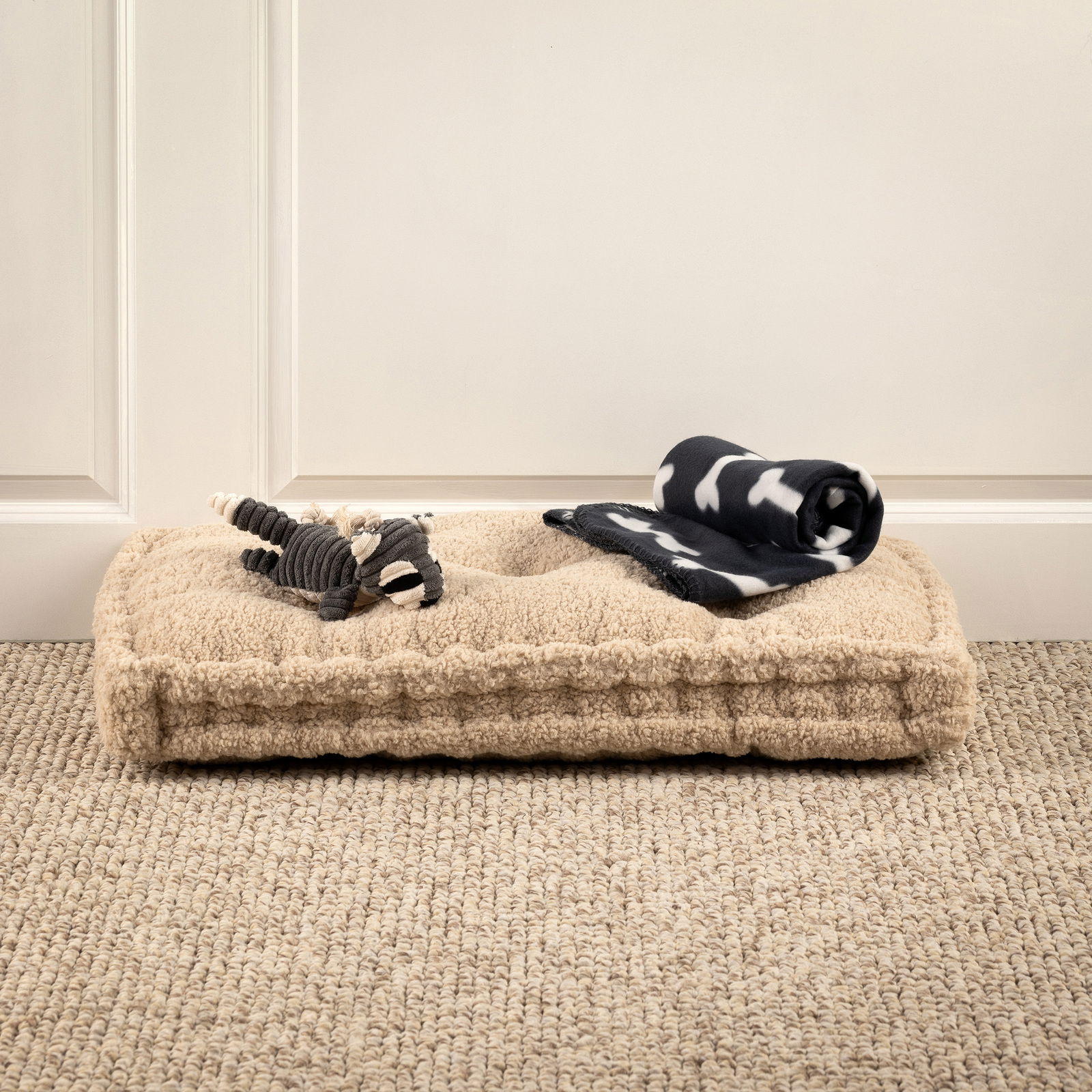 Hundebett mit Spielzeug und Decke, seitliche Perspektive