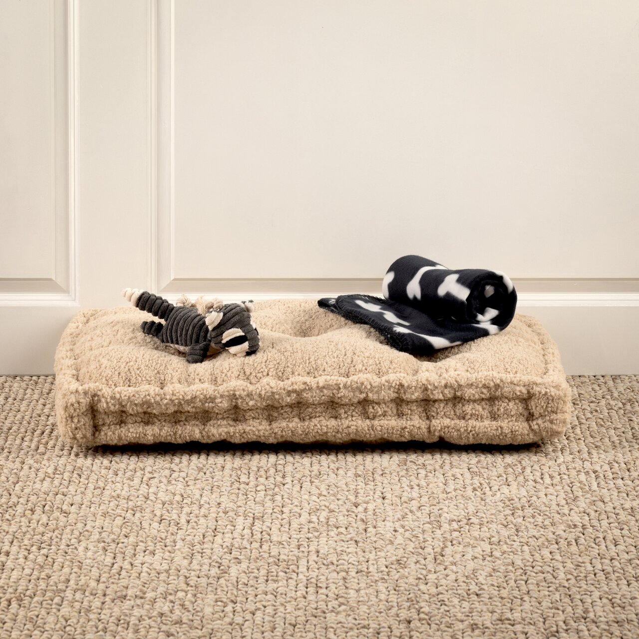 Hundebett mit Spielzeug und Decke, seitliche Perspektive