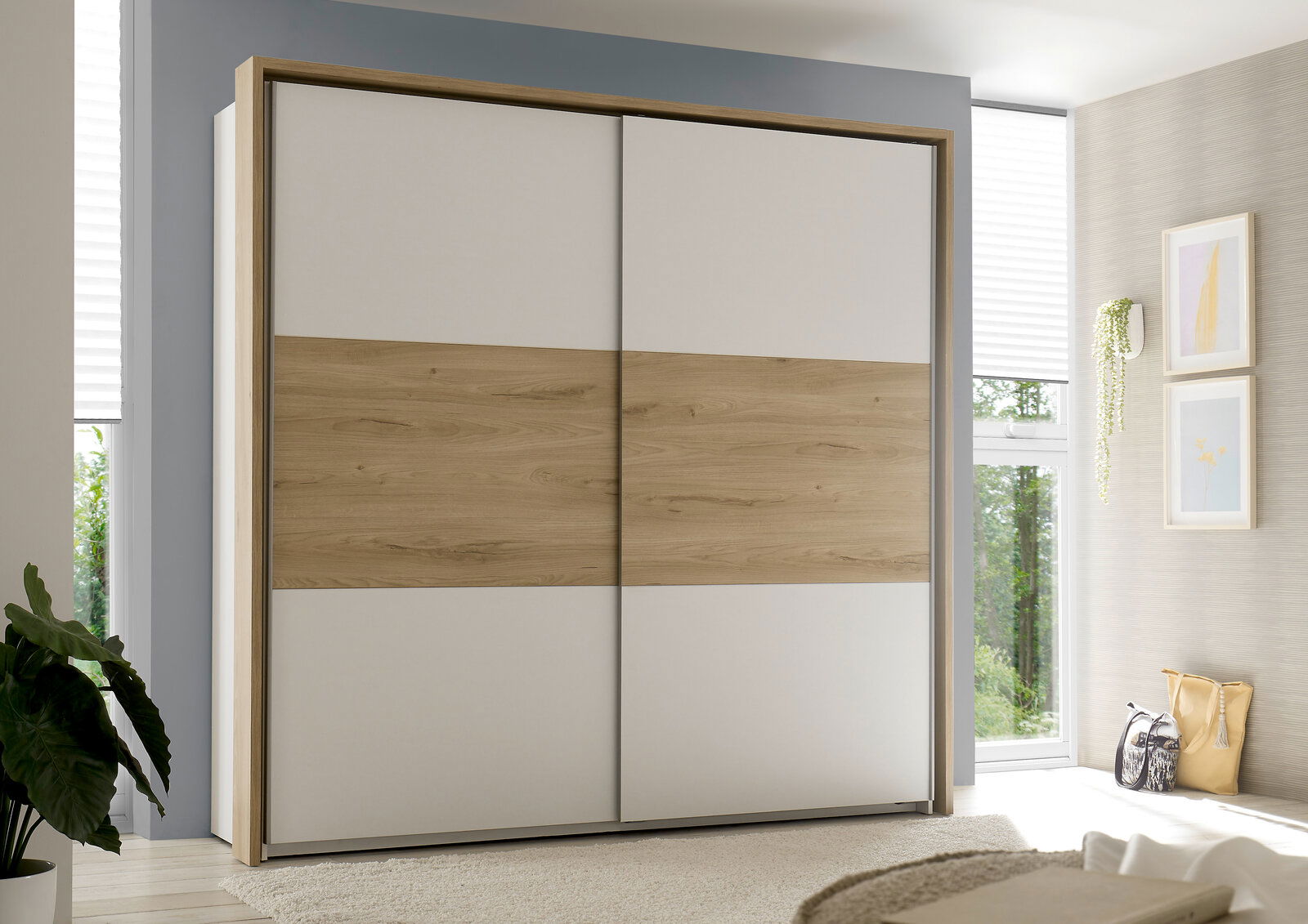 Moderner Kleiderschrank mit Schiebetüren in Holzoptik und weißem Design, frontal fotografiert in einem hellen Schlafzimmer.