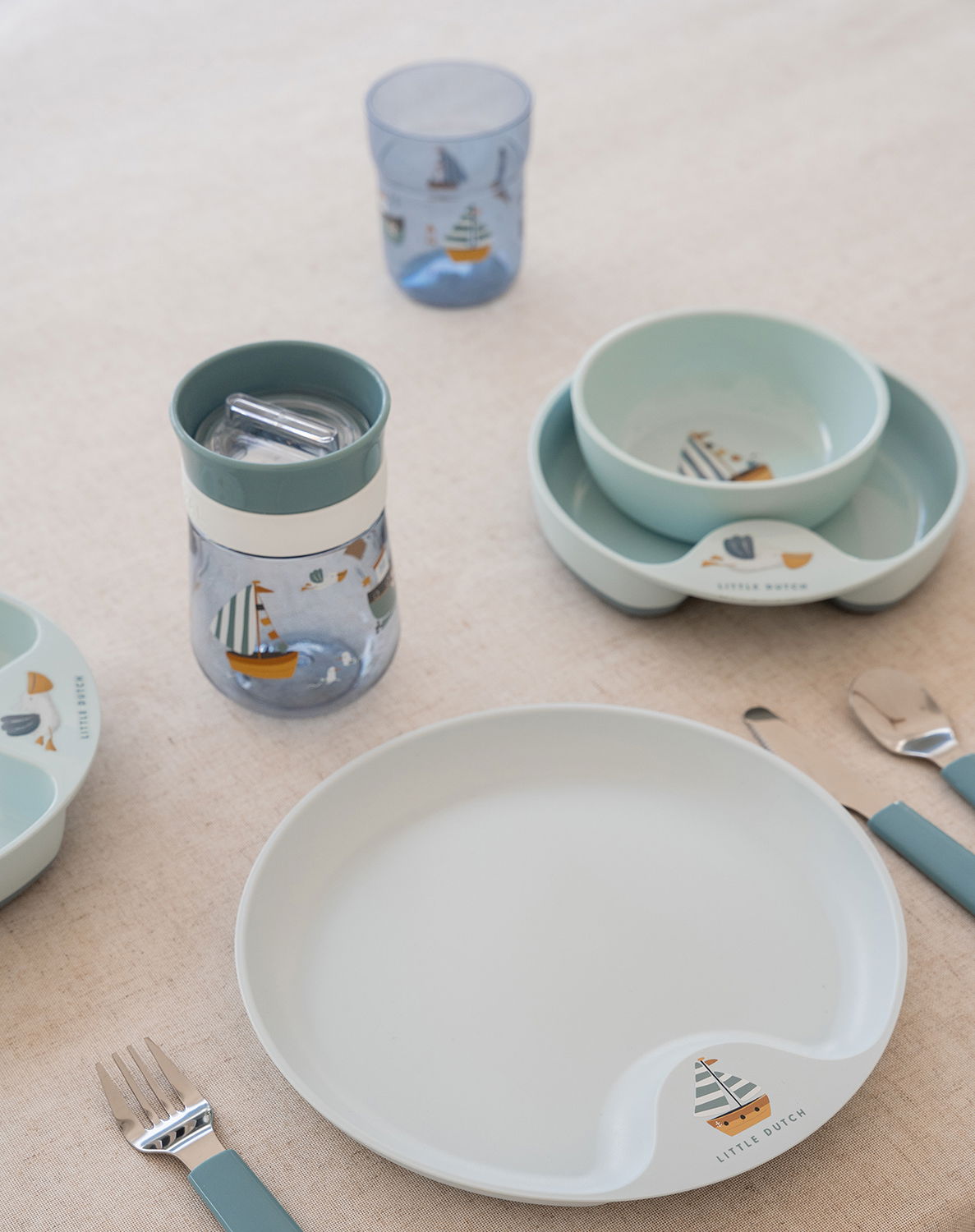 Kindergeschirr-Set Mio 6-tlg. in sanften Pastellfarben mit maritimen Motiven, bestehend aus Teller, Schüssel, Becher und Besteck, aus der Vogelperspektive auf einem Tisch arrangiert.
