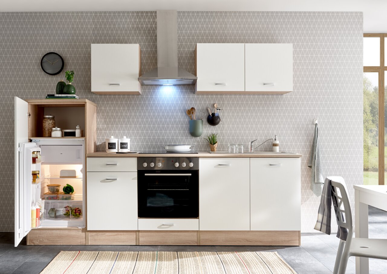 Moderne Küchenzeile mit weißen Schränken und Holzdetails, inklusive Kühlschrank, Herd und Dunstabzugshaube, aus frontaler Perspektive.