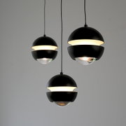 Drei moderne schwarze Kugel-Pendelleuchten mit warmweißem Lichtband und transparentem Glasdiffusor, frontal in leichter Untersicht vor grauem Hintergrund