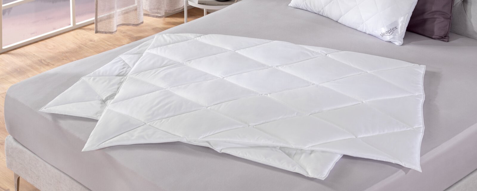 Sommerbettdecke 155x220 cm auf einem Bett, von oben fotografiert, zeigt die weiße, gesteppte Oberfläche.