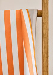 Nahaufnahme eines gestreiften Sporttuchs in Orange und Weiß, das über eine Holzleiter gehängt ist.