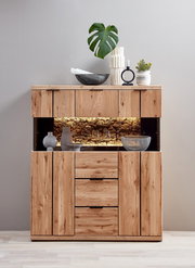 Frontansicht eines modernen Highboards aus massivem Holz mit Glasvitrine und warm beleuchtetem Naturkork-Rückwandbereich, dekoriert mit Vasen, Schalen, Kerzenhalter und Pflanze auf hellem Hintergrund
