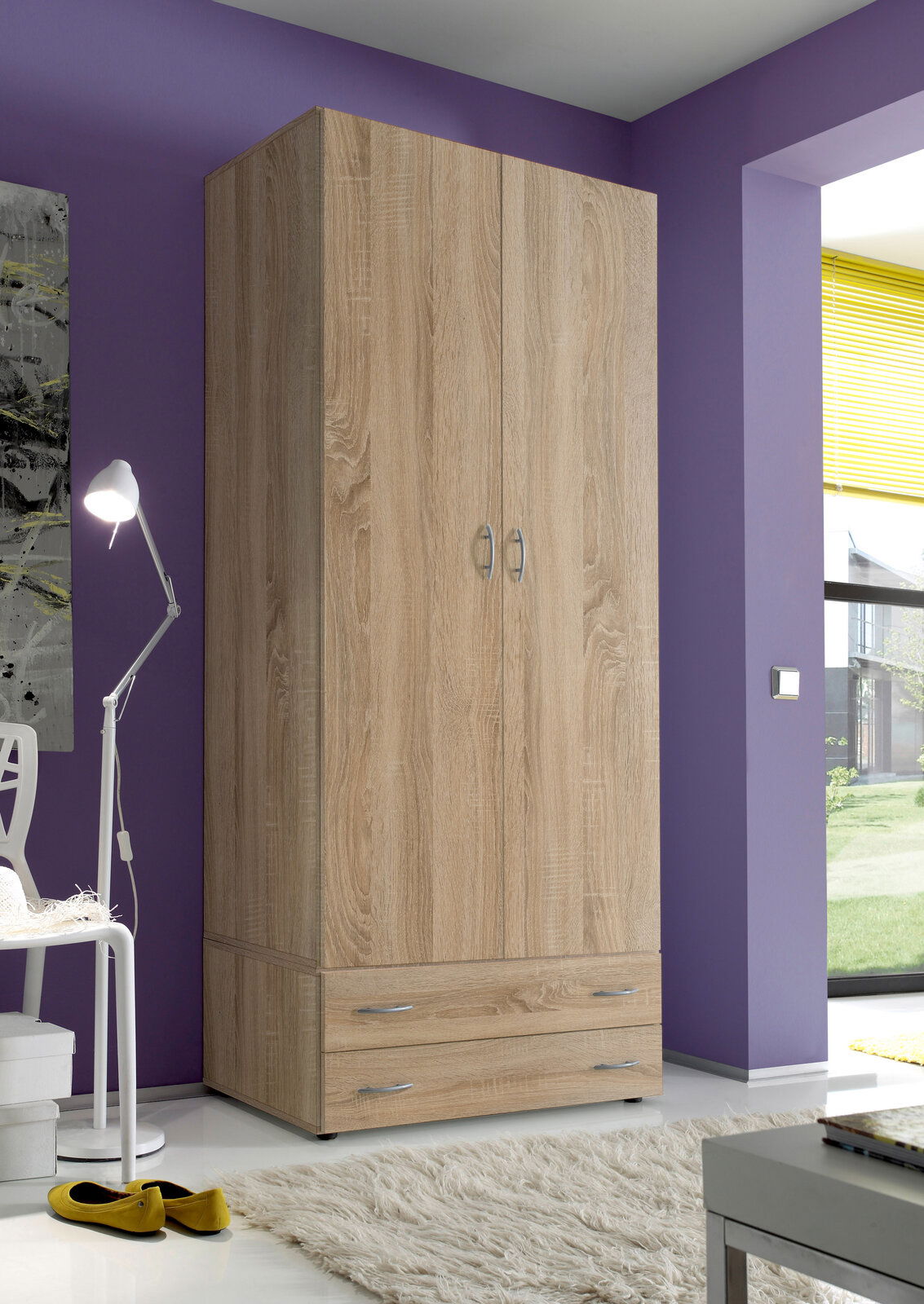 Zweiflügeliger Drehtürenschrank aus Holz in Eichenoptik, frontal fotografiert, mit zwei Schubladen unten, in einem modern eingerichteten Raum mit lila Wand.